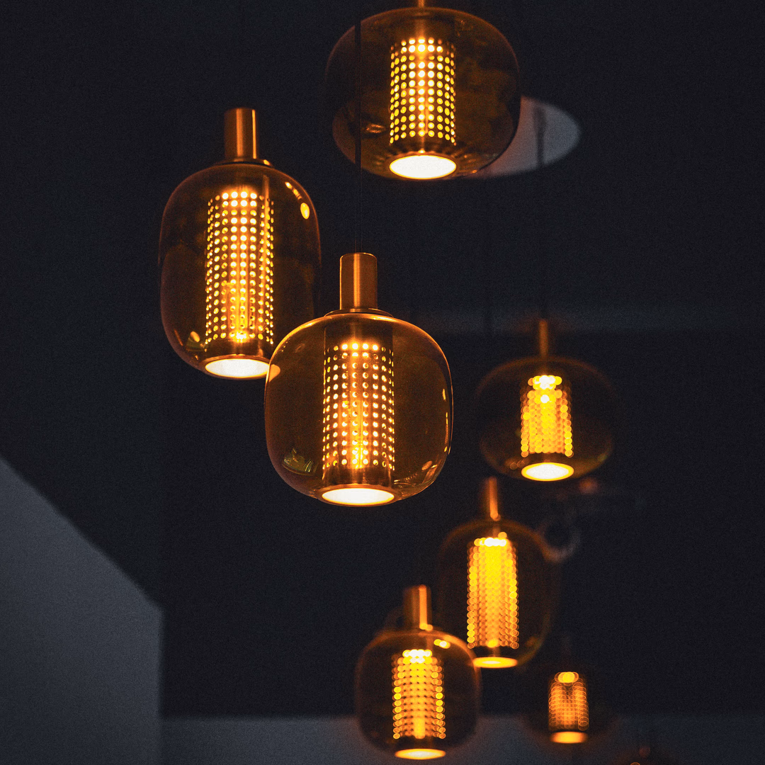 Mehrere moderne, warme goldene hängende Lampen vor dunklem Hintergrund.