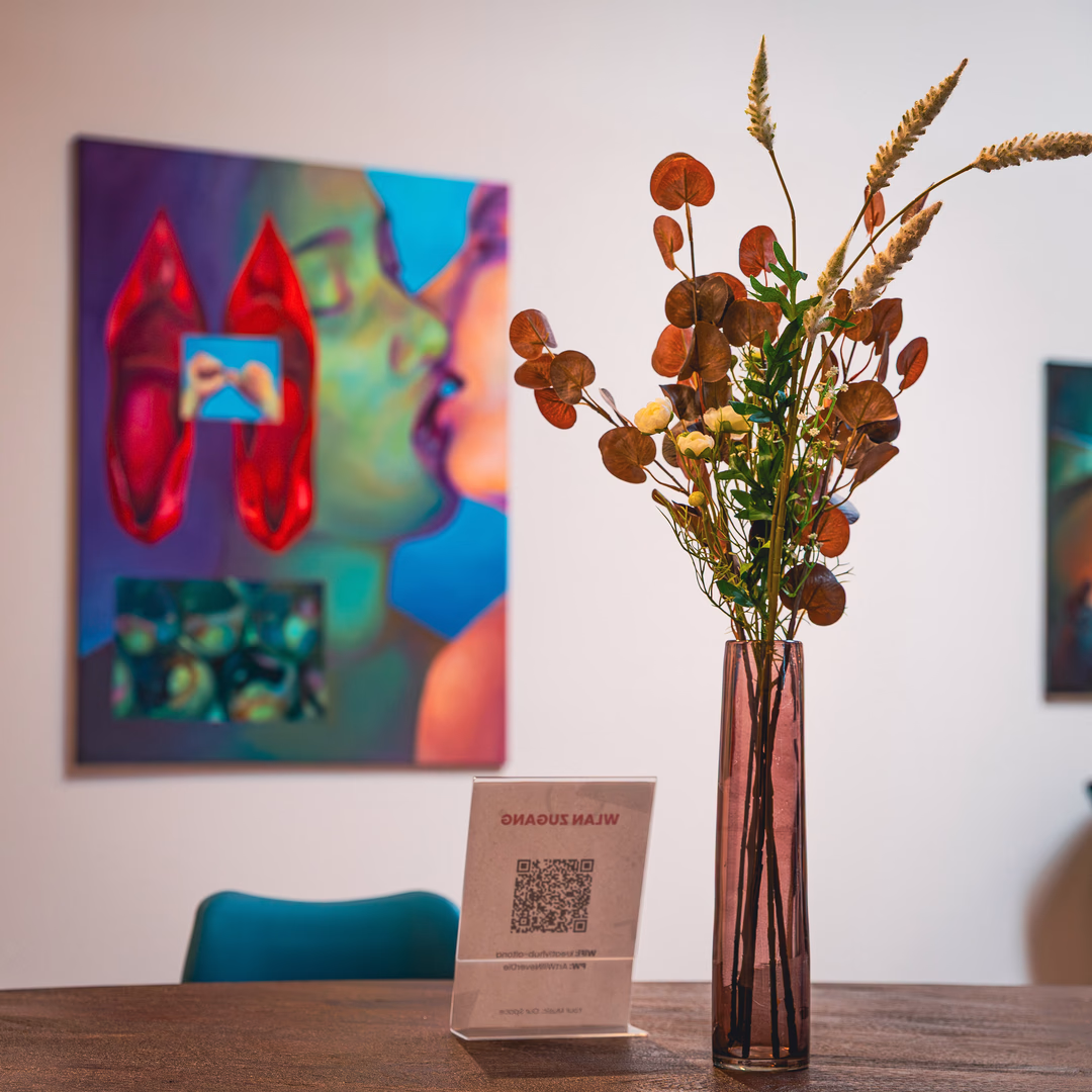 Vase mit getrockneten und frischen Blumen auf einem Holztisch, unscharfes modernes Gemälde und Stuhl im Hintergrund.